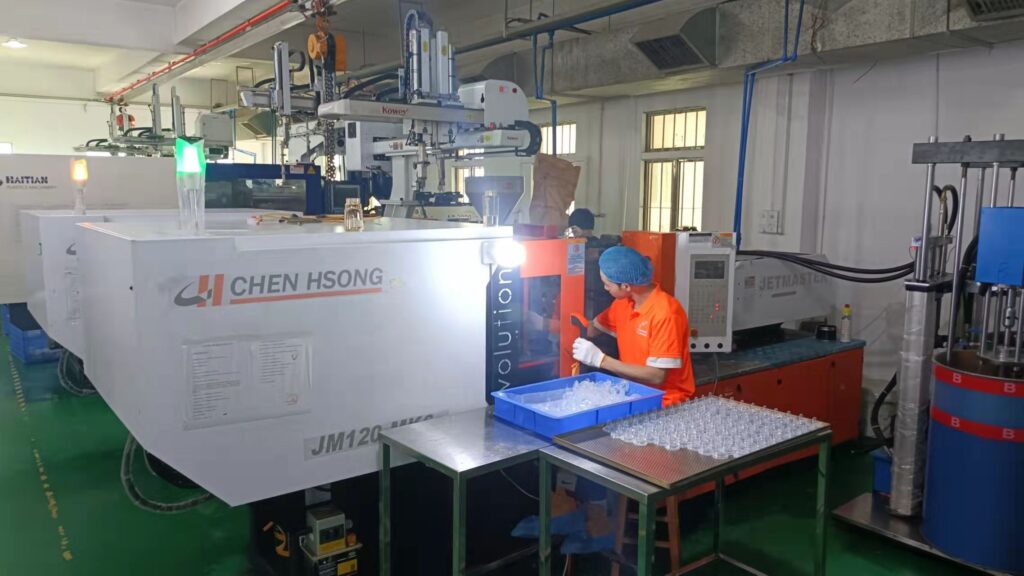 Injection molding machine with robotic take-out arm producing clear baby bottle parts at our factory