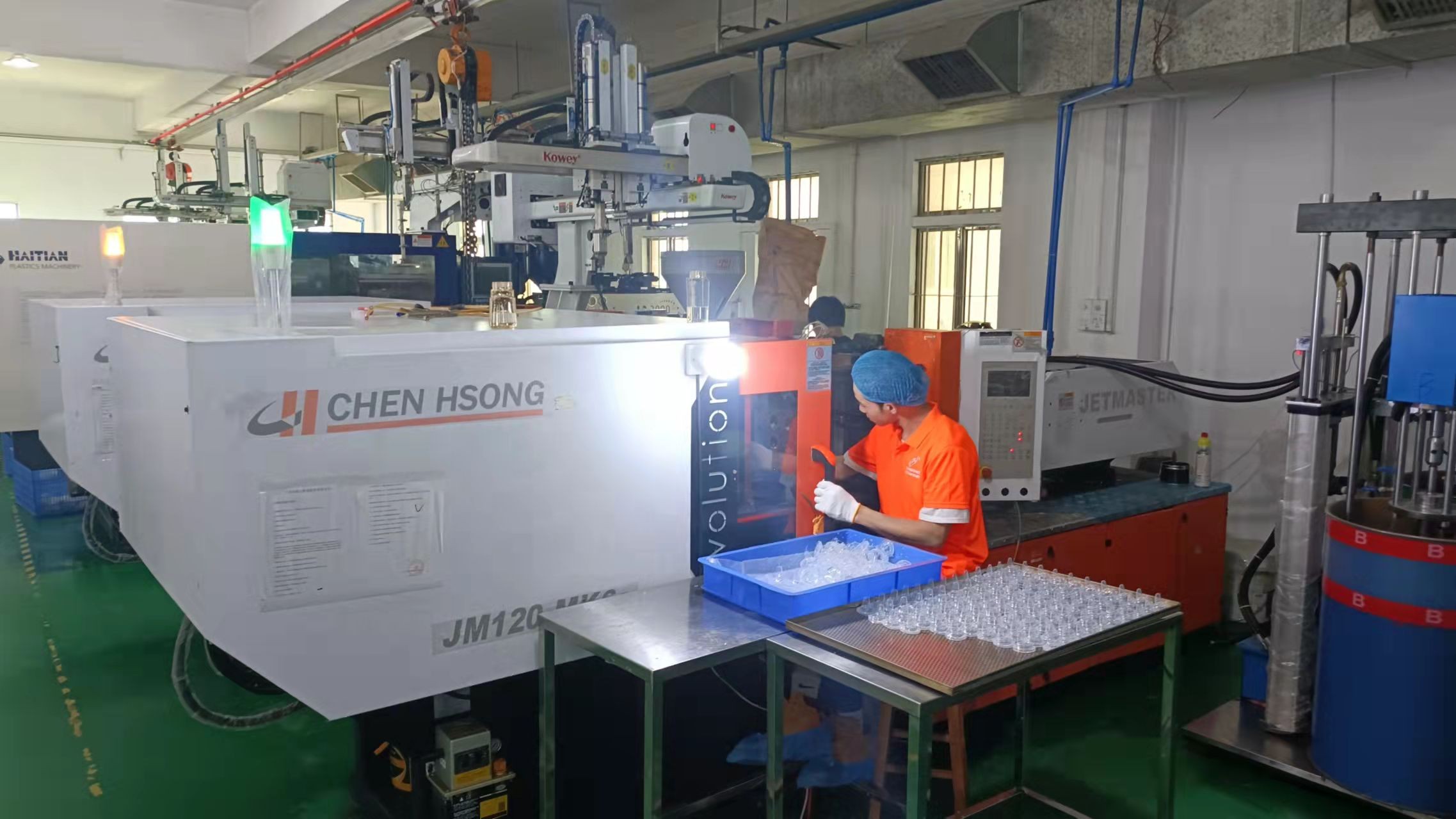 Injection molding machine with robotic take-out arm producing clear baby bottle parts at our factory